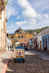 A local ice cream vendor pulls his wooden cart through the streets of La Antigua