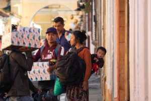 A mother carries her baby in a traditional woven wrap back carry